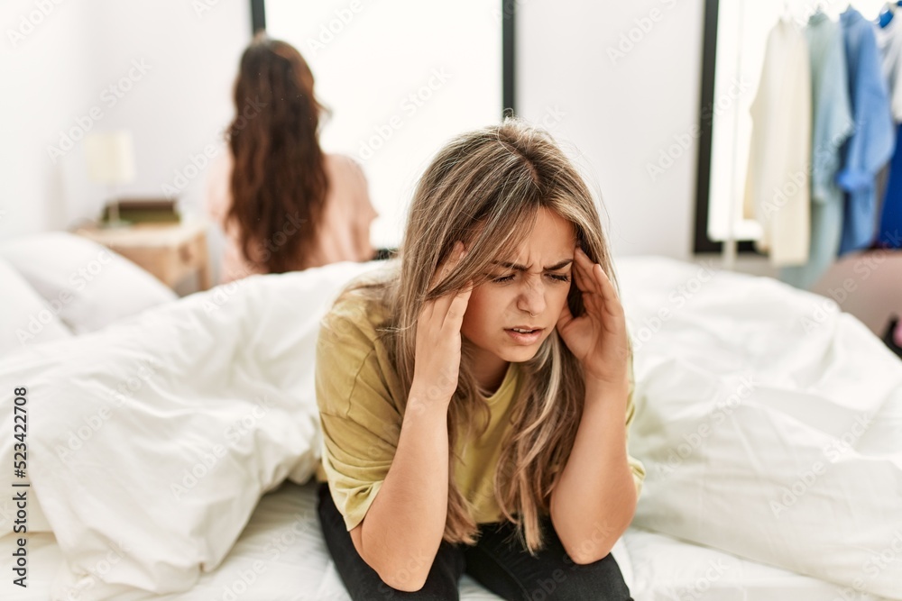 Young couple in trouble sitting on the bed with hands on head.