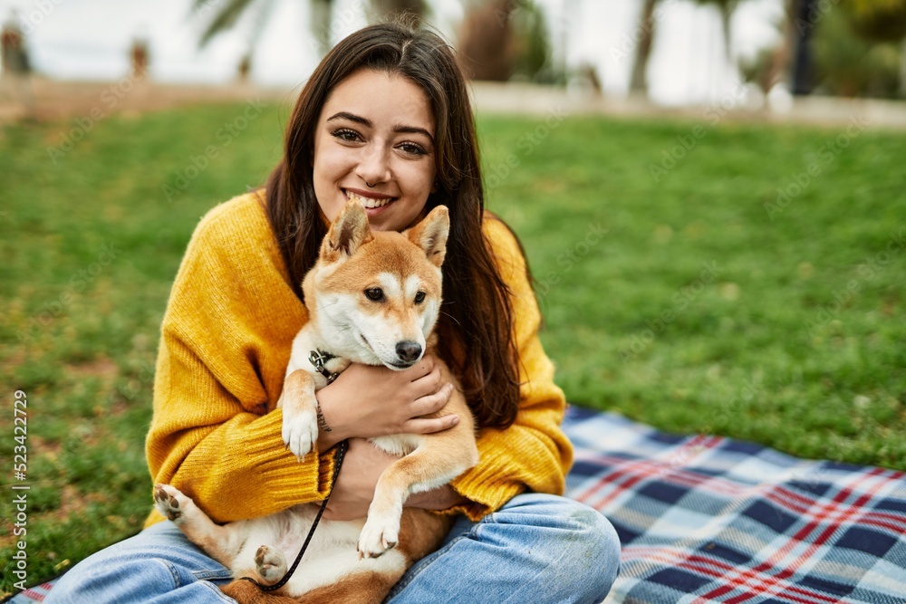 Beautiful young woman hugging happy shiba inu dog at park Beautiful young woman hugging happy shiba inu dog at park