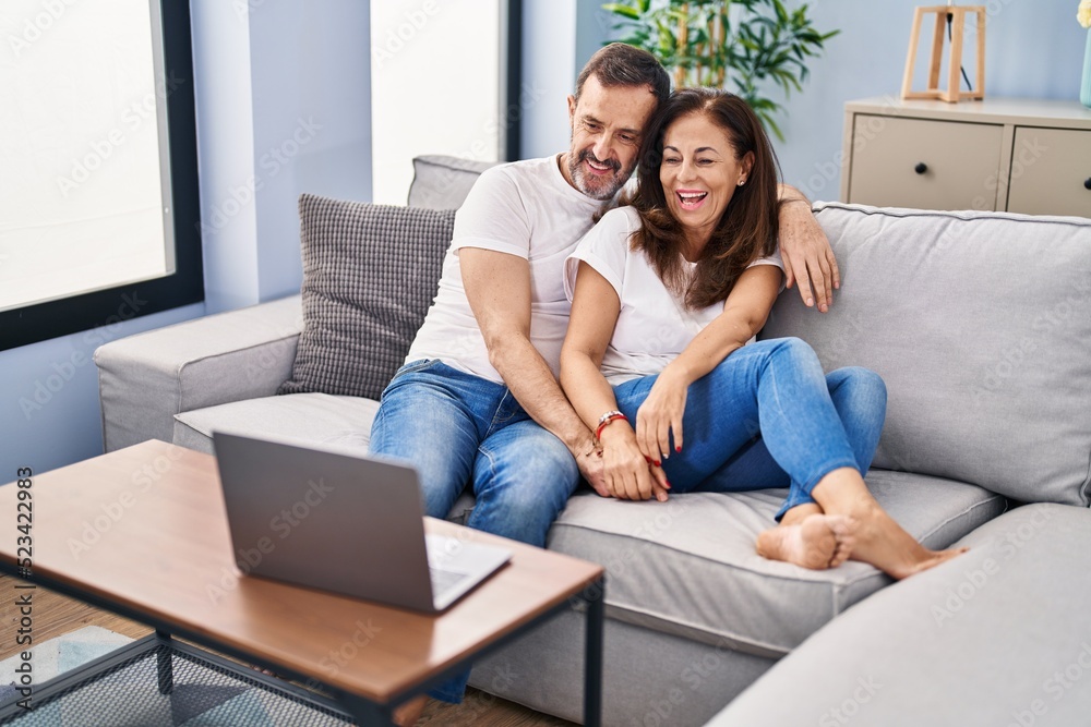 Middle age man and woman couple watching movie sitting on sofa at home