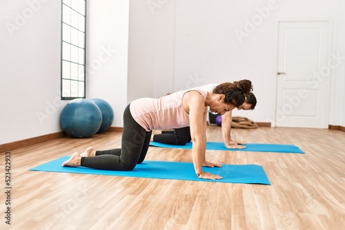 Mature hispanic couple doing excersice and stretching at yoga room. Two adult people doing pilates and flexibility workout
