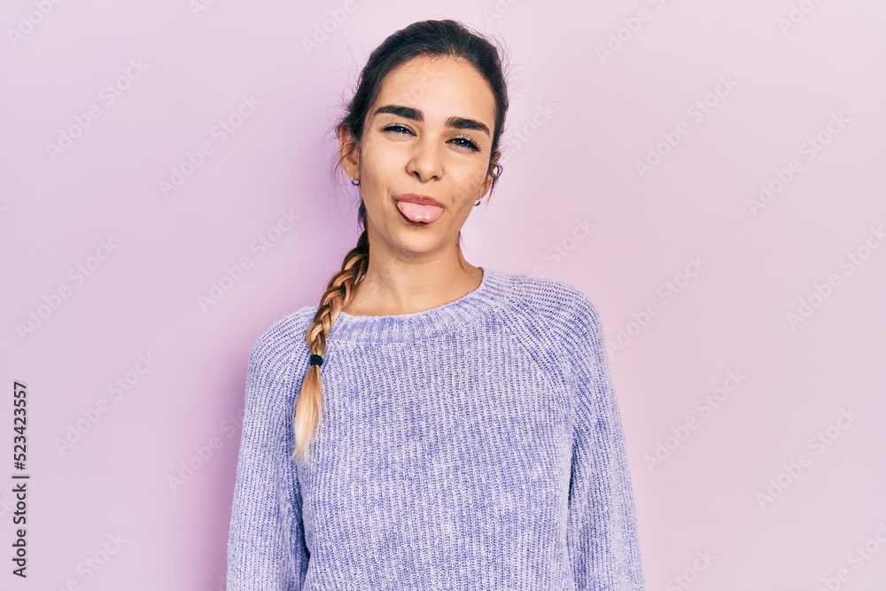 Young hispanic girl wearing casual clothes sticking tongue out happy with funny expression. emotion concept.