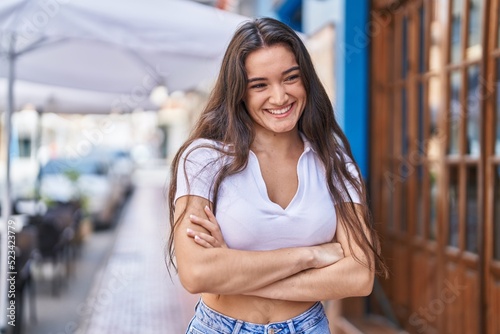 Young hispanic woman smiling confident standing with arms crossed gesture at street