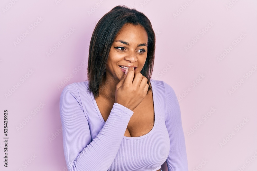 Young african american girl wearing casual clothes looking stressed and nervous with hands on mouth biting nails. anxiety problem. Young african american girl wearing casual clothes looking stressed and nervous with hands on mouth biting nails. anxiety problem.