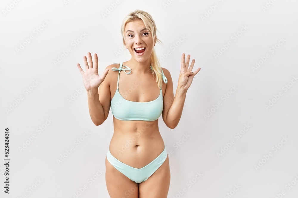 Young caucasian woman wearing bikini over isolated background showing and pointing up with fingers number nine while smiling confident and happy. Young caucasian woman wearing bikini over isolated background showing and pointing up with fingers number nine while smiling confident and happy.