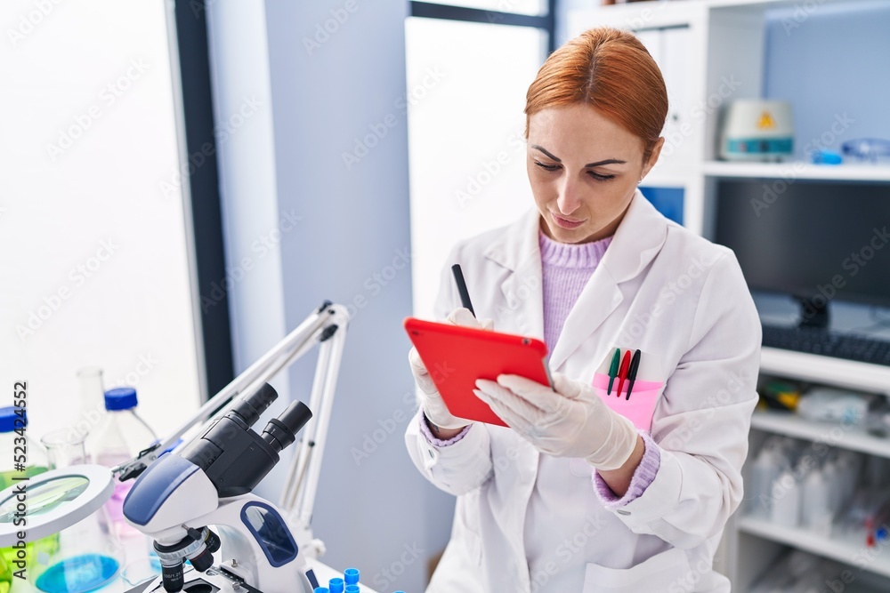 Young caucasian woman scientist using touchpad with serious expression at laboratory Young caucasian woman scientist using touchpad with serious expression at laboratory