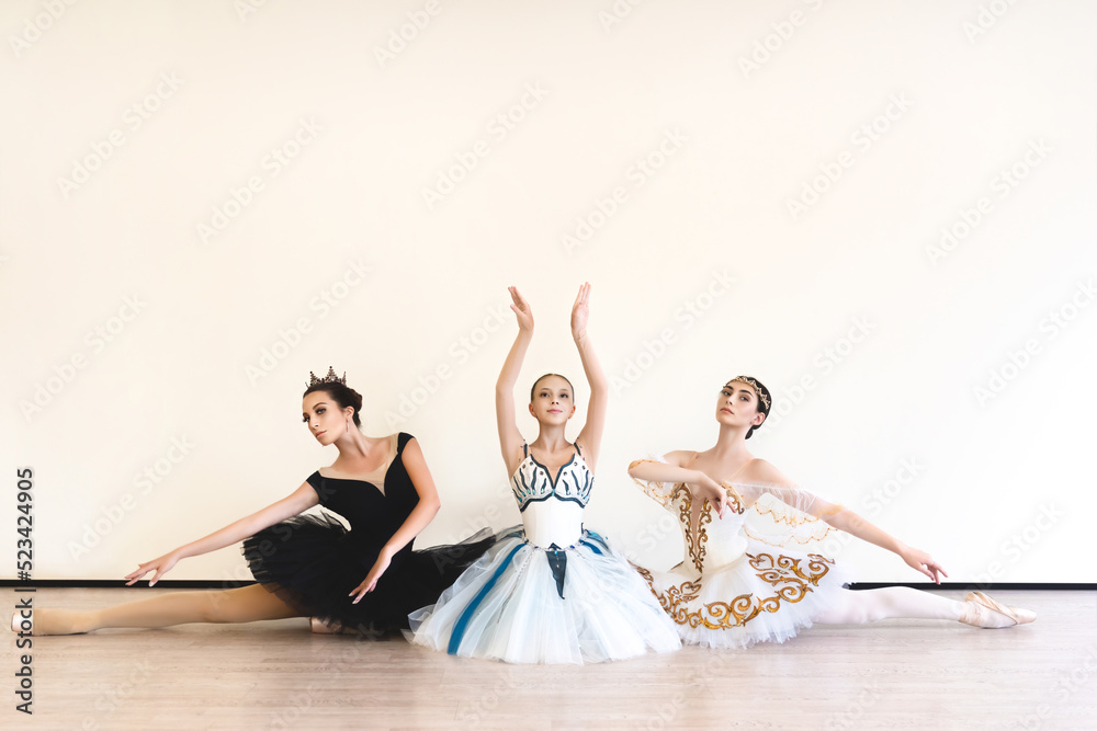 Naklejka premium young ballerinas perform paired exercises against a white background in the studio
