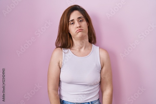 Brunette woman standing over pink background looking sleepy and tired  exhausted for fatigue and hangover  lazy eyes in the morning.