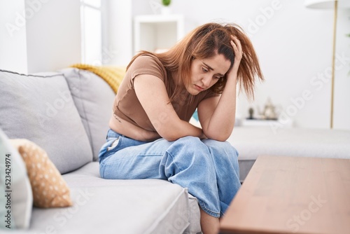 Young woman stressed sitting on sofa at home