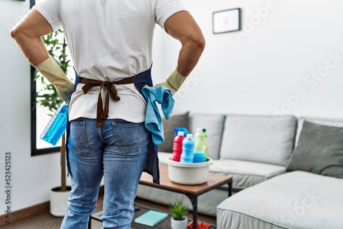 Young hispanic man on back view holding sprayer at home