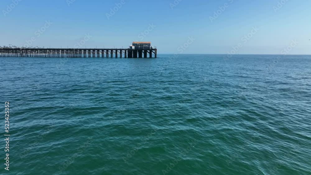 4K aerial shot flying by sailboat at sea with pier in background 4K aerial shot flying by sailboat at sea with pier in background