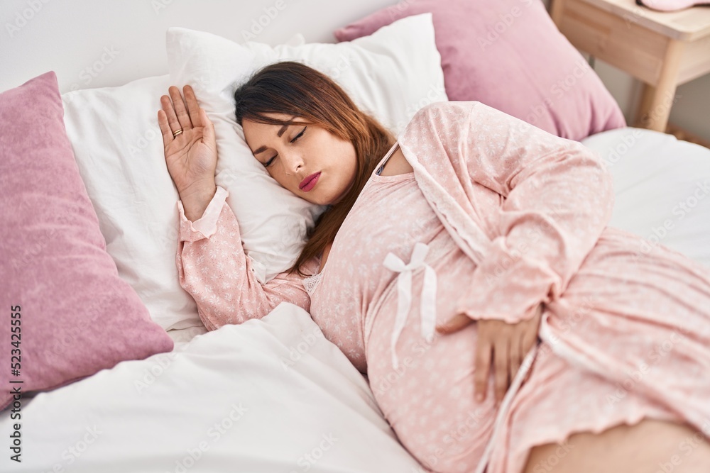 Obraz premium Young pregnant woman lying on bed sleeping at bedroom