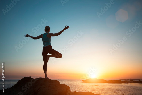 Silhouette woman yoga  meditation on the ocean beach seeing off the sun.