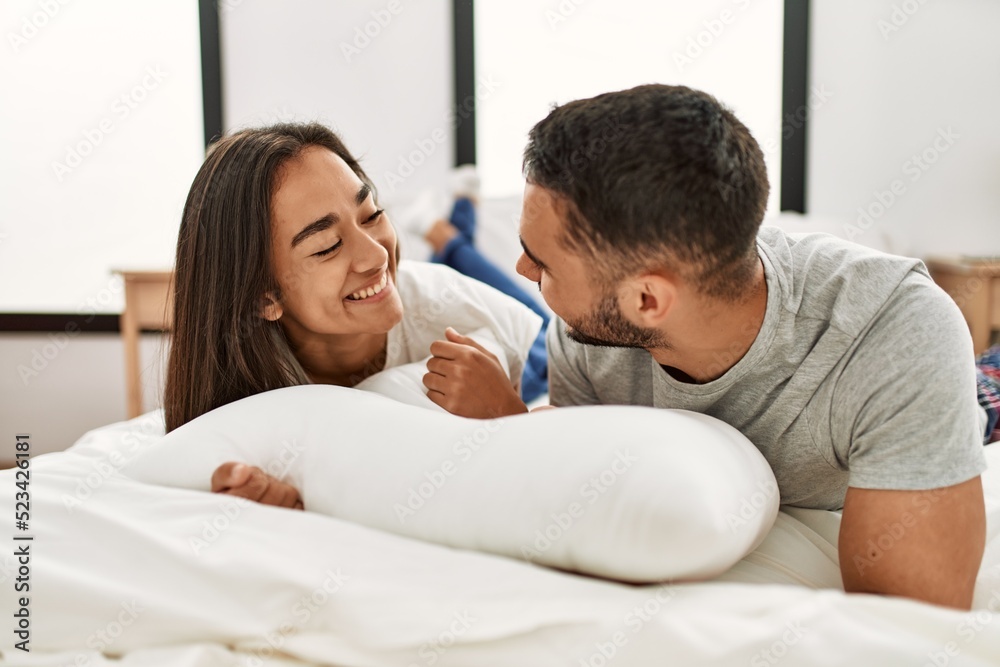 Young latin couple smiling happy hugging on the bed at home.