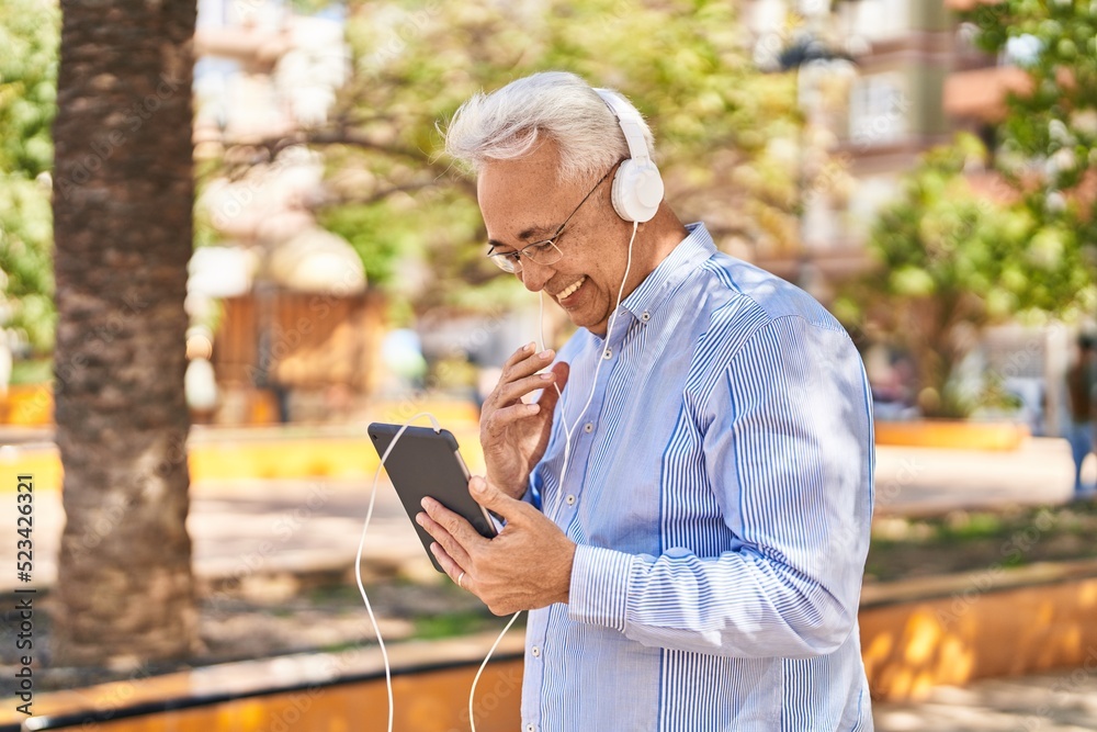 Obraz premium Senior man smiling confident watching video on touchpad at park