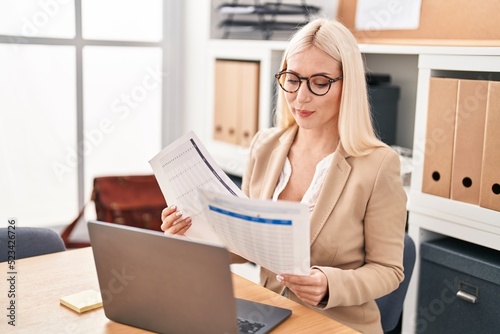 Young blonde woman business worker using laptop working and reading document at office