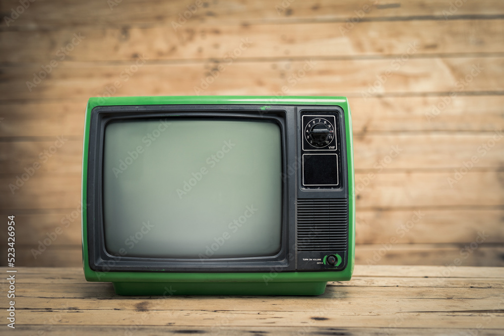 Green retro old television receiver on wood background, vintage old TV on wood table in room.