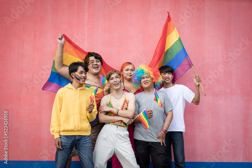 Obraz na plátně Happy Asian young friends holding rainbow flag celebrating gay pride festival -