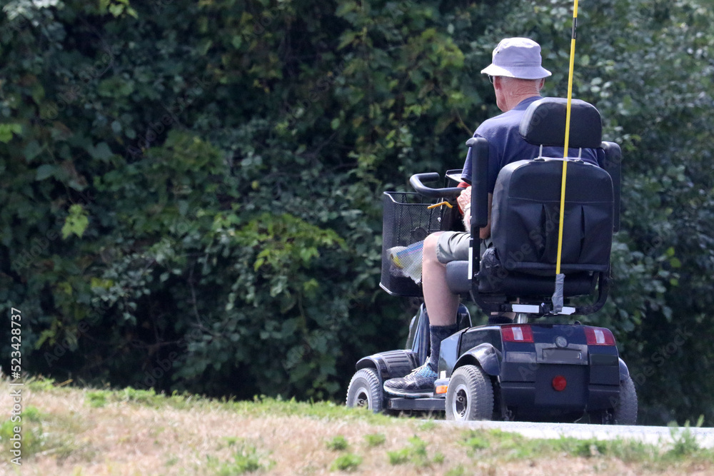 Fototapeta premium Motorized scooter offering mobility to elderly man out for a nature trail ride