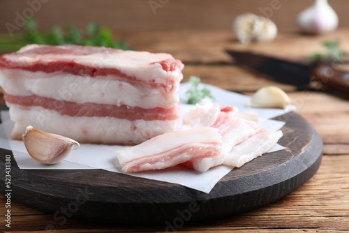 Tasty salt pork with garlic on wooden table, closeup