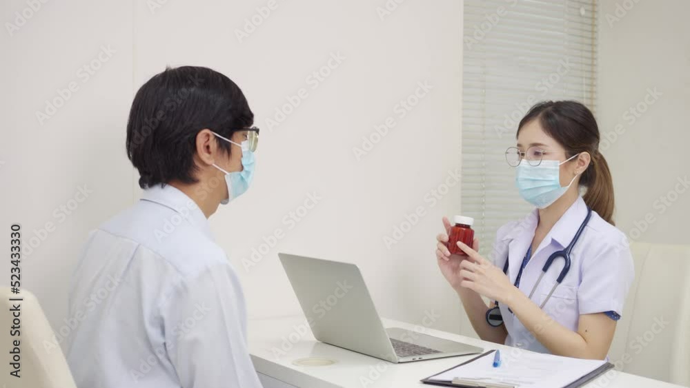 Asian female doctor wear face masks sitting at the desk and talking and advice medicine to a patient male at the hospital. health protection, healthcare, medicine, Illness Prevention, and COVID-19 Asian female doctor wear face masks sitting at the desk and talking and advice medicine to a patient male at the hospital. health protection, healthcare, medicine, Illness Prevention, and COVID-19