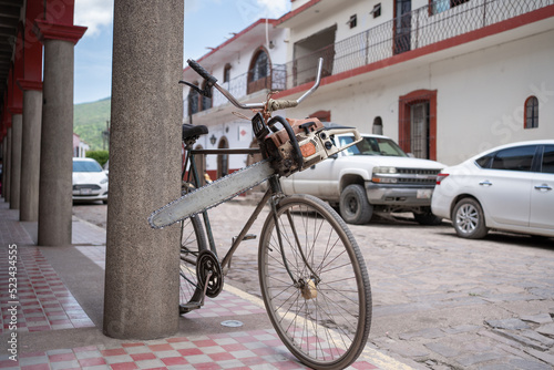 La sierra de cortar está amarrada en la bicicleta en una calle.	 photo