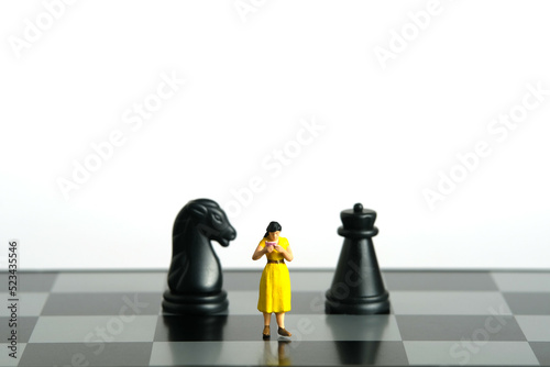 Miniature people toy figure photography. Defensive or attack strategies concept. A girl student standing in between horse and castle chessboard pawn knight  isolated on white background