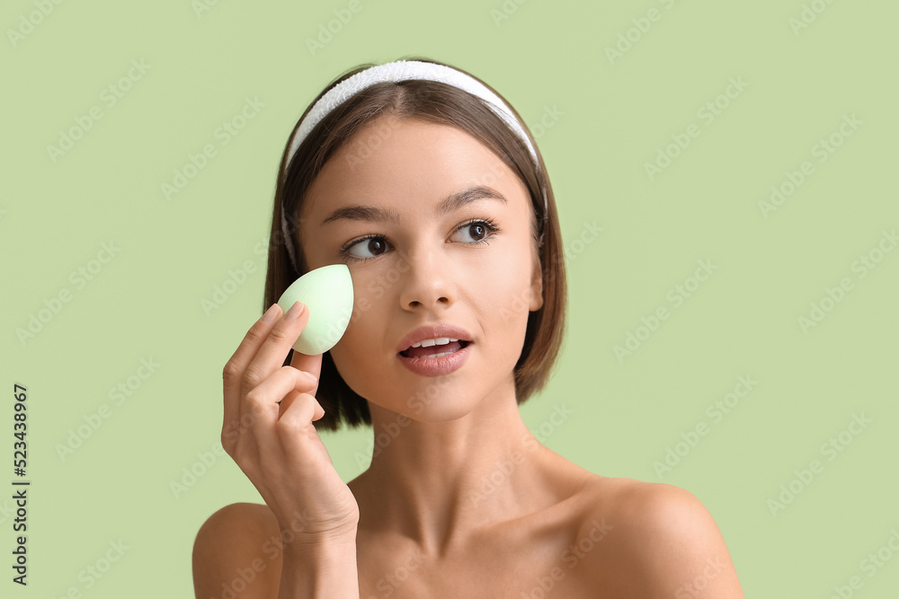 Pretty young woman with makeup sponge on green background, closeup Pretty young woman with makeup sponge on green background, closeup