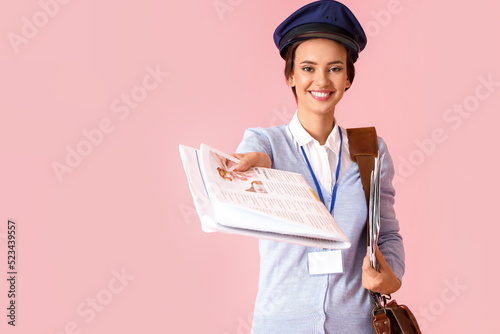 Young postwoman with newspa...