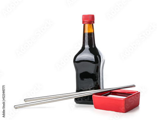 Bottle and bowl of soy sauce with chopsticks on white background