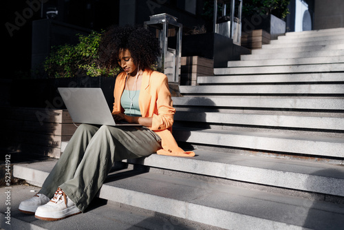 afro woman using laptop outdoor