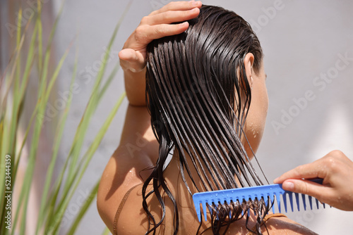 Foto Young Female Model Putting Refreshing Mask On Long Wet Hair With Wooden Comb