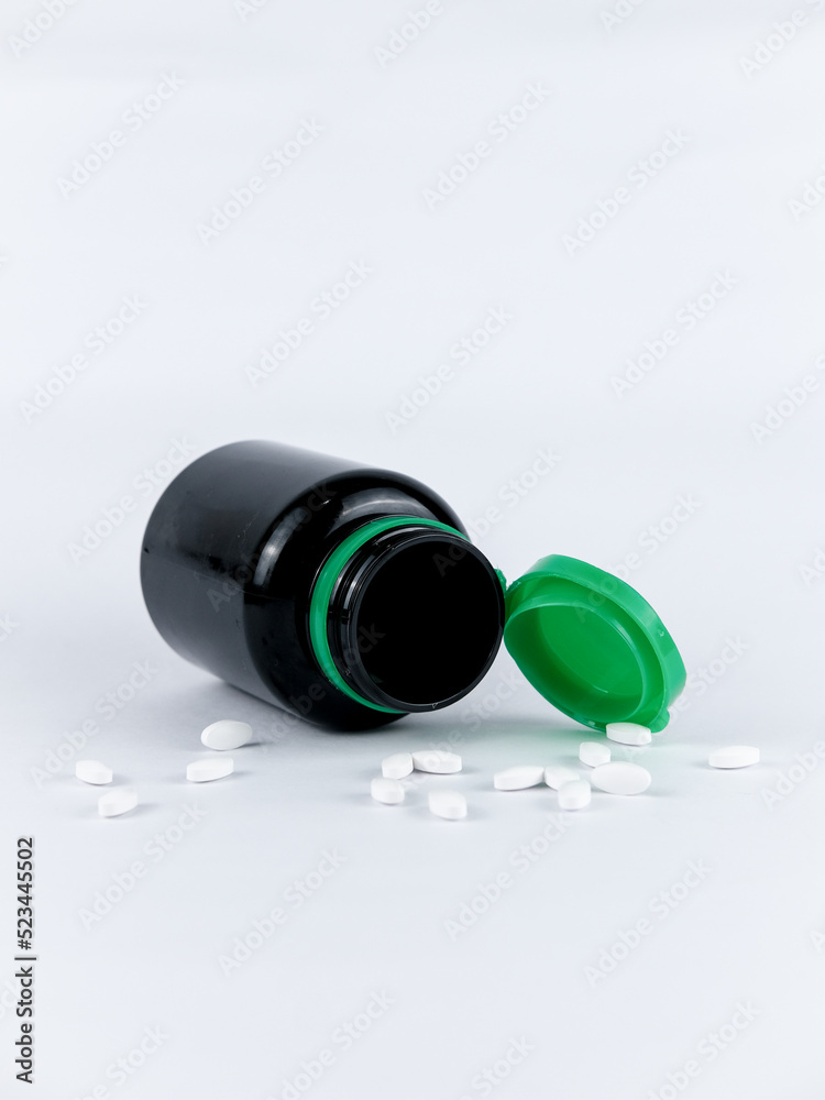 medicine bottle with pills. medicine black plastic bottle with white pills on white background. 