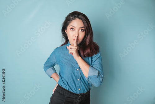 Fotografie Portrait of a young Asian woman tell be quiet, shushing with serious face, hush