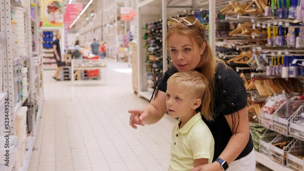 A mother and son in a large hypermarket in the department of household goods.