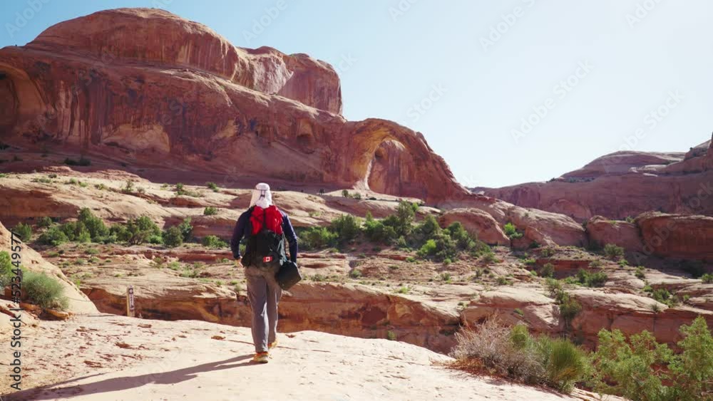 Hiker Walking towards Corona Arch - Moab, United States Hiker Walking towards Corona Arch - Moab, United States