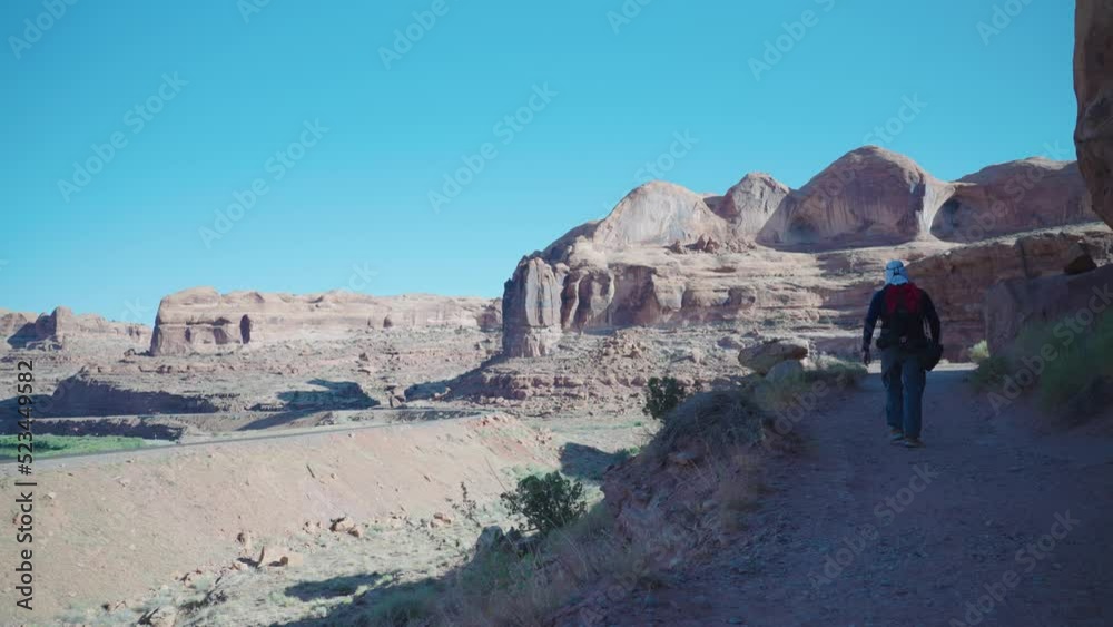Hiker walking in the shade on a desert trail near Moab, United States Hiker walking in the shade on a desert trail near Moab, United States