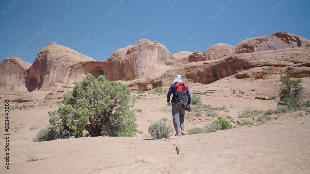Hiker Walking towards Pinto Arch in Moab, United States Hiker Walking towards Pinto Arch in Moab, United States