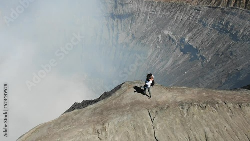 Aerial View of Man and Woman Embracing on Ridge Active Volcano. Girl Waving to Camera. Mount Bromo (Gunung Bromo) in East Java, Indonesia