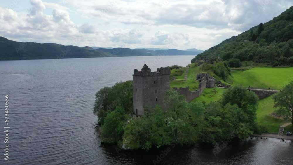 Captivating drone shot of Urquhart Castle on Loch Ness in Scotland. The shot sweeps low to the water and rises high above the castle, revealing the beautiful scenery. Captivating drone shot of Urquhart Castle on Loch Ness in Scotland. The shot sweeps low to the water and rises high above the castle, revealing the beautiful scenery.
