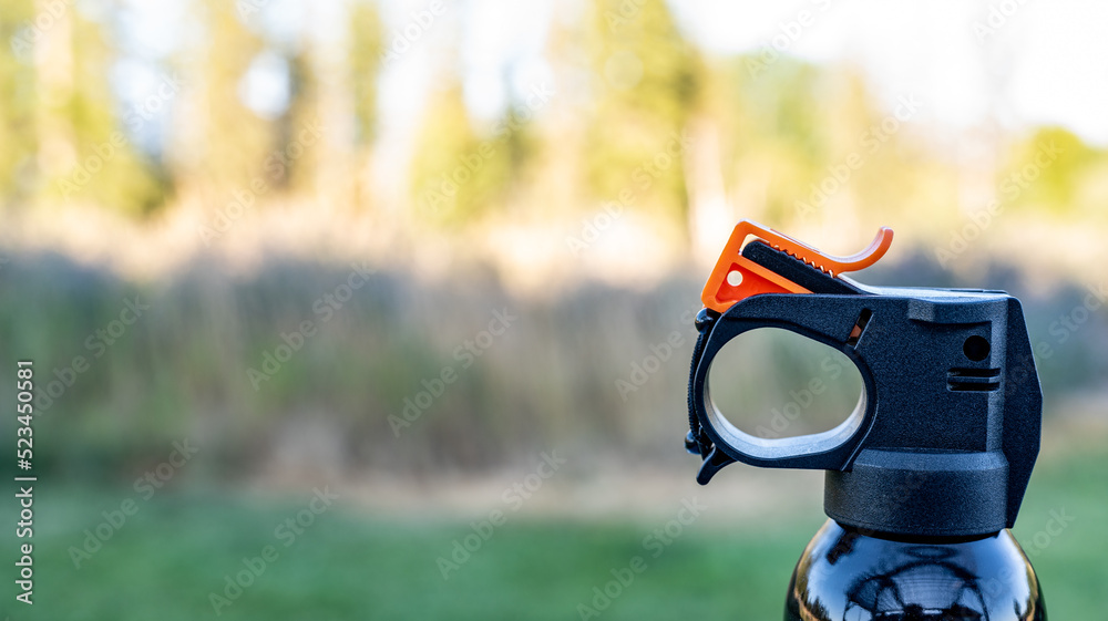 Aerosol trigger of a can of bear spray in an outdoor setting Aerosol trigger of a can of bear spray in an outdoor setting