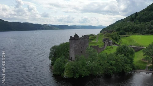 Captivating drone shot of Urquhart Castle on Loch Ness in Scotland. The shot sweeps low to the water and rises high above the castle, revealing the beautiful scenery. photo