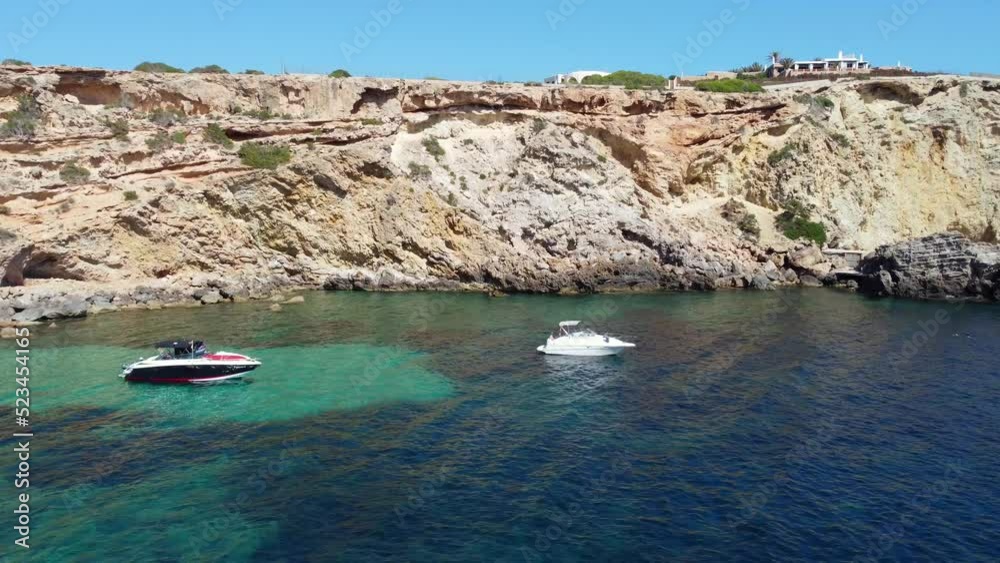 2 motor boats in the bay luxury villa on the cliff
Beautiful aerial view flight fly backwards drone footage of edge beach Sa Figuera borda Ibiza summer 2022 4k Cinematic from above by Philipp Marnitz