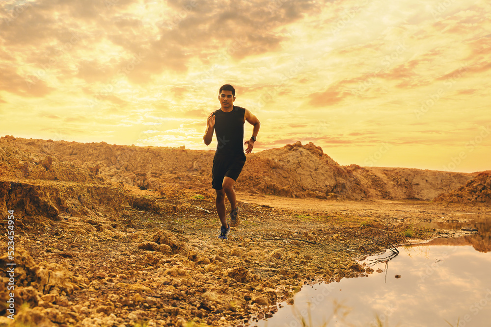 Silhouette of young man runner running trail at sunset lakeside. Healthy and lifestyle concept