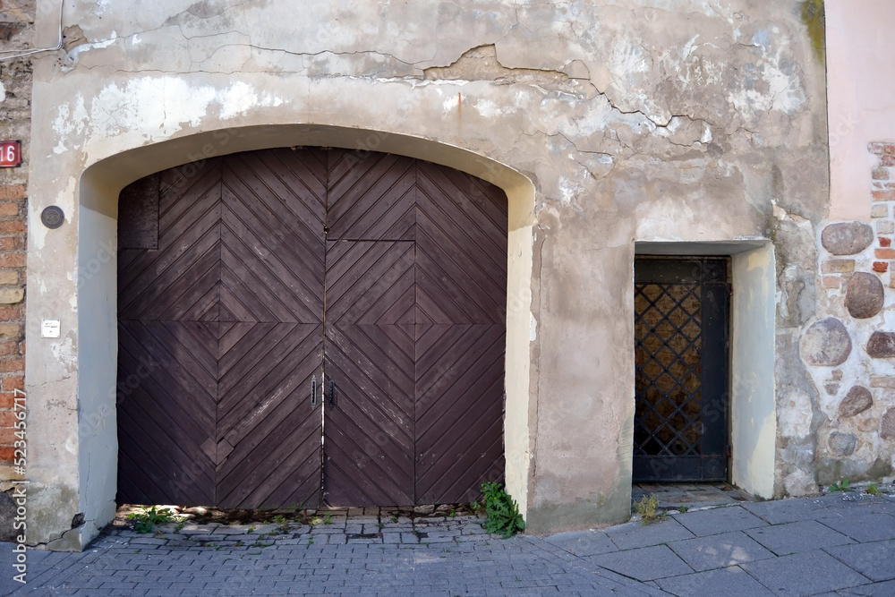 Fototapeta premium Antique wooden gate in a stone wall. Fragment of the facade.