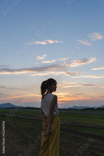 夕暮れの飛行場を眺める女性 © peach100