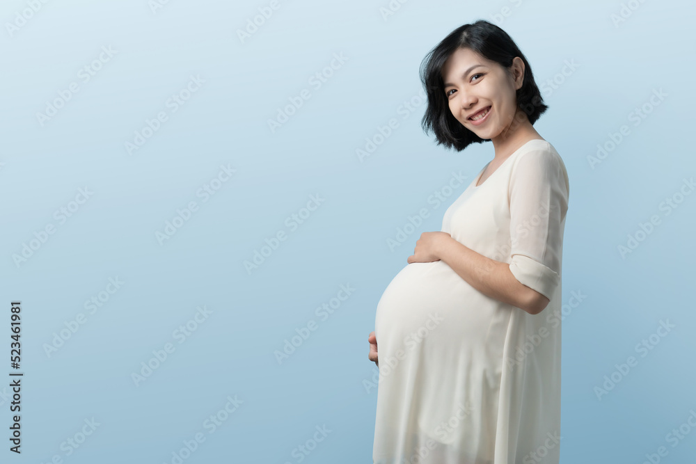 Portrait of Young beautiful Korean or Chinese pregnant woman standing on Blue background, Positive Asian expectant mother over isolated studio wall Portrait of Young beautiful Korean or Chinese pregnant woman standing on Blue background, Positive Asian expectant mother over isolated studio wall