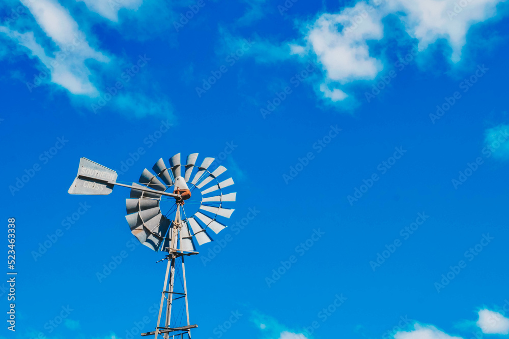 a windmill in front of a blue sky with some clouds a windmill in front of a blue sky with some clouds