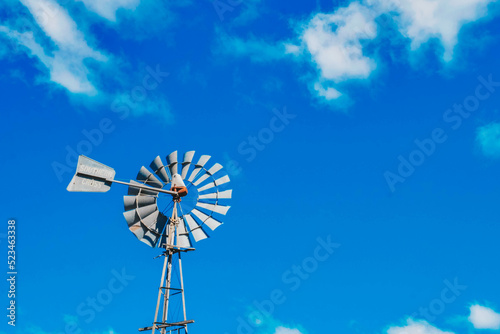 a windmill in front of a blue sky with some clouds