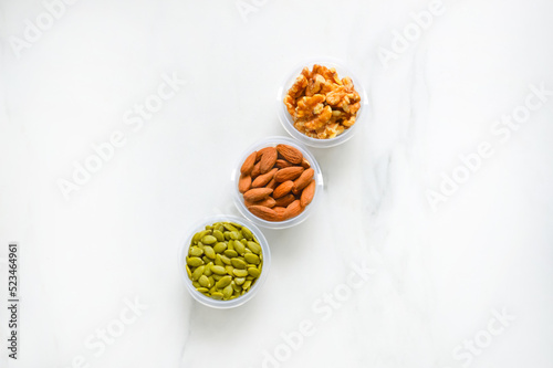 Three types of nuts, top view. Bowls with the almond, walnut and pumpkin seeds with the selective focus.