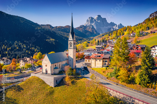 Impressive aerial view from flying drone of San Lorenzo Catholic church. Exciting autumn cityscape of Selva di Cadore village, Province of Belluno, Italy, Europe. Traveling concept background..